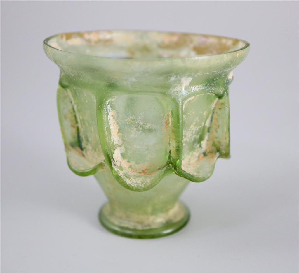 A Roman green glass auricular cup, 2nd/3rd century AD, 7.5cm high